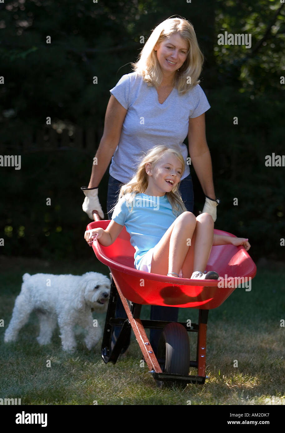 Mother pushing her daughter in a wheelbarrow Stock Photo - Alamy