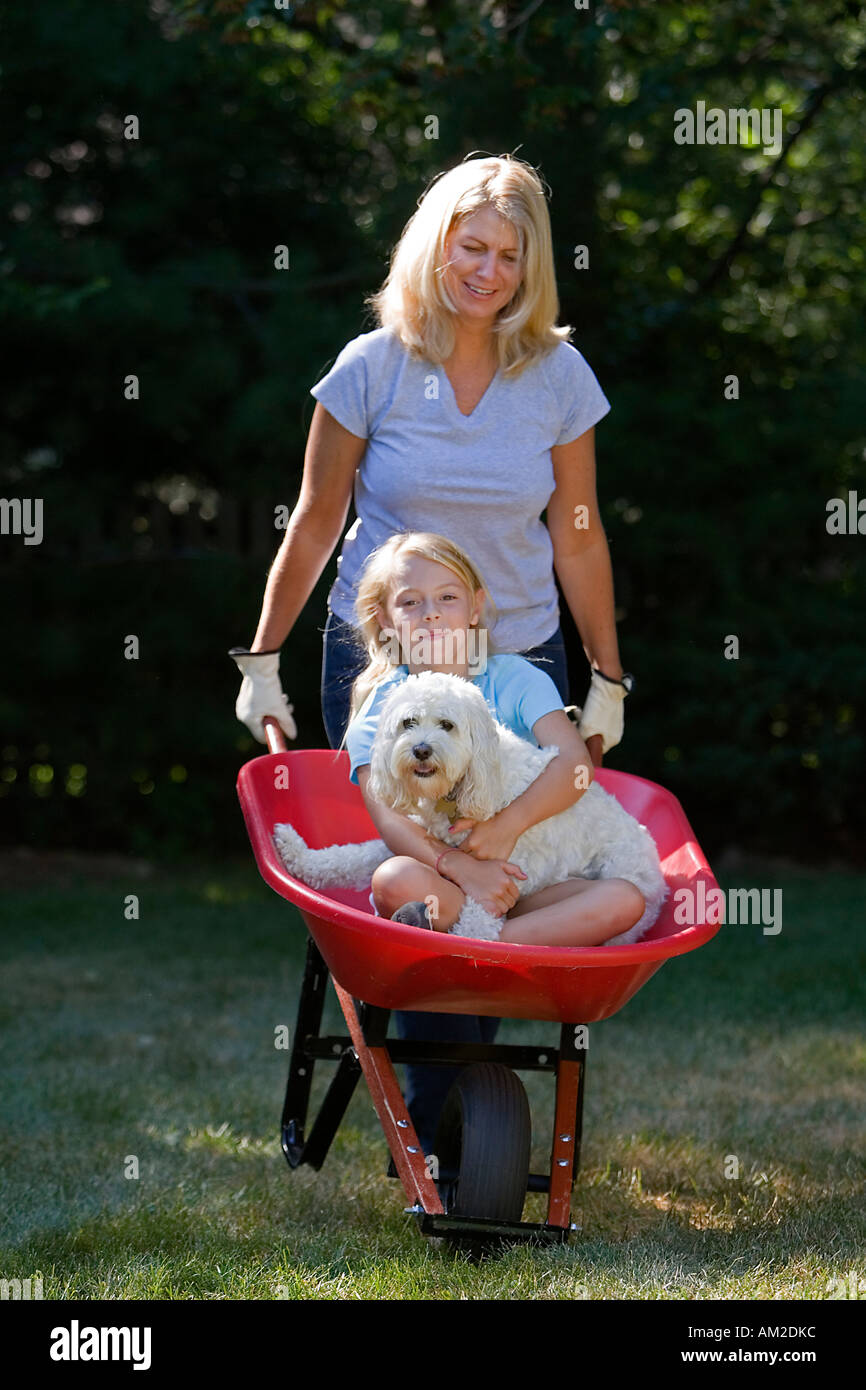Mother pushing her daughter in a wheelbarrow Stock Photo - Alamy