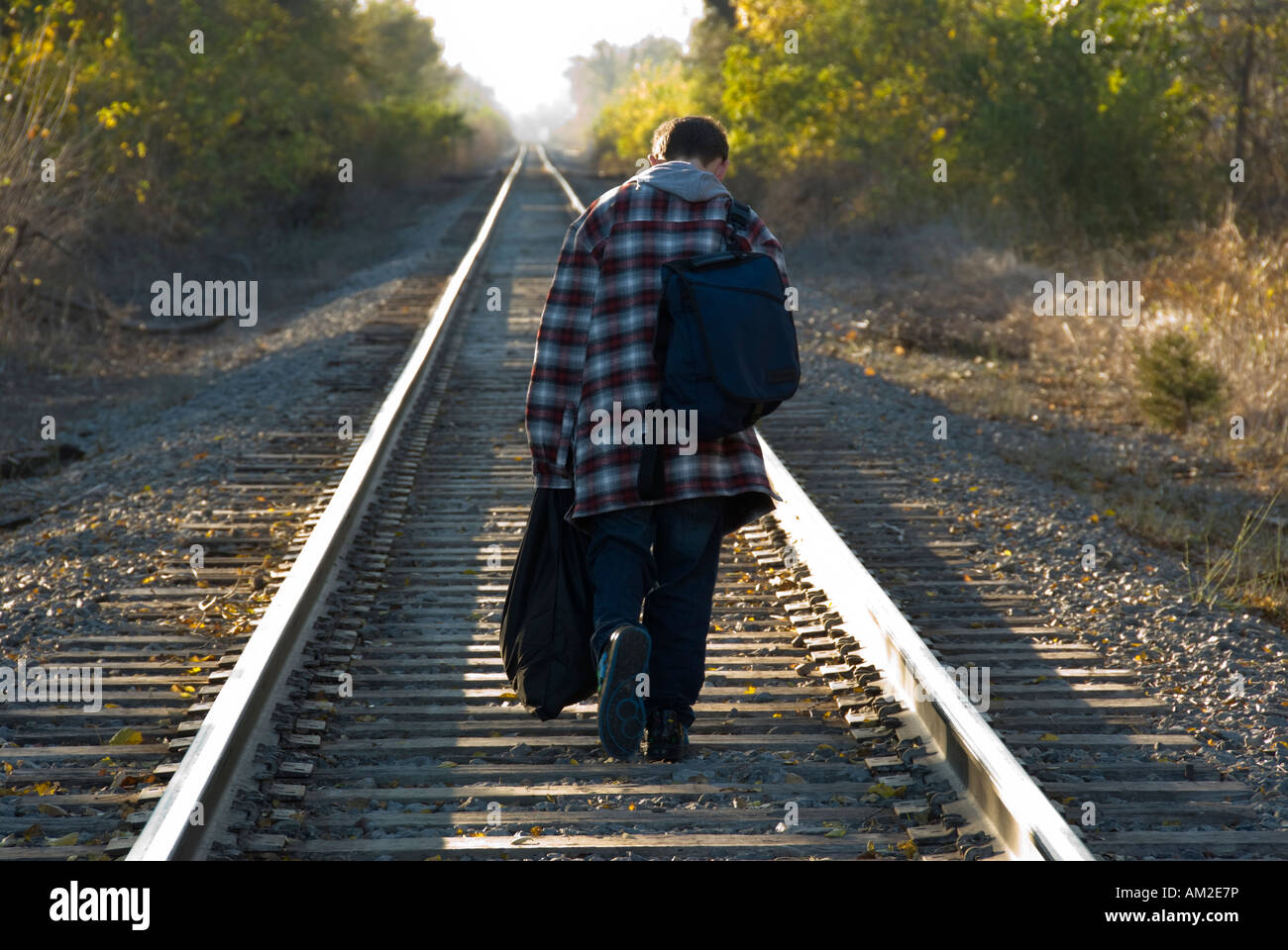 A 13 year old boy runaway walks down a railroad track. Conceptual. Stock Photo