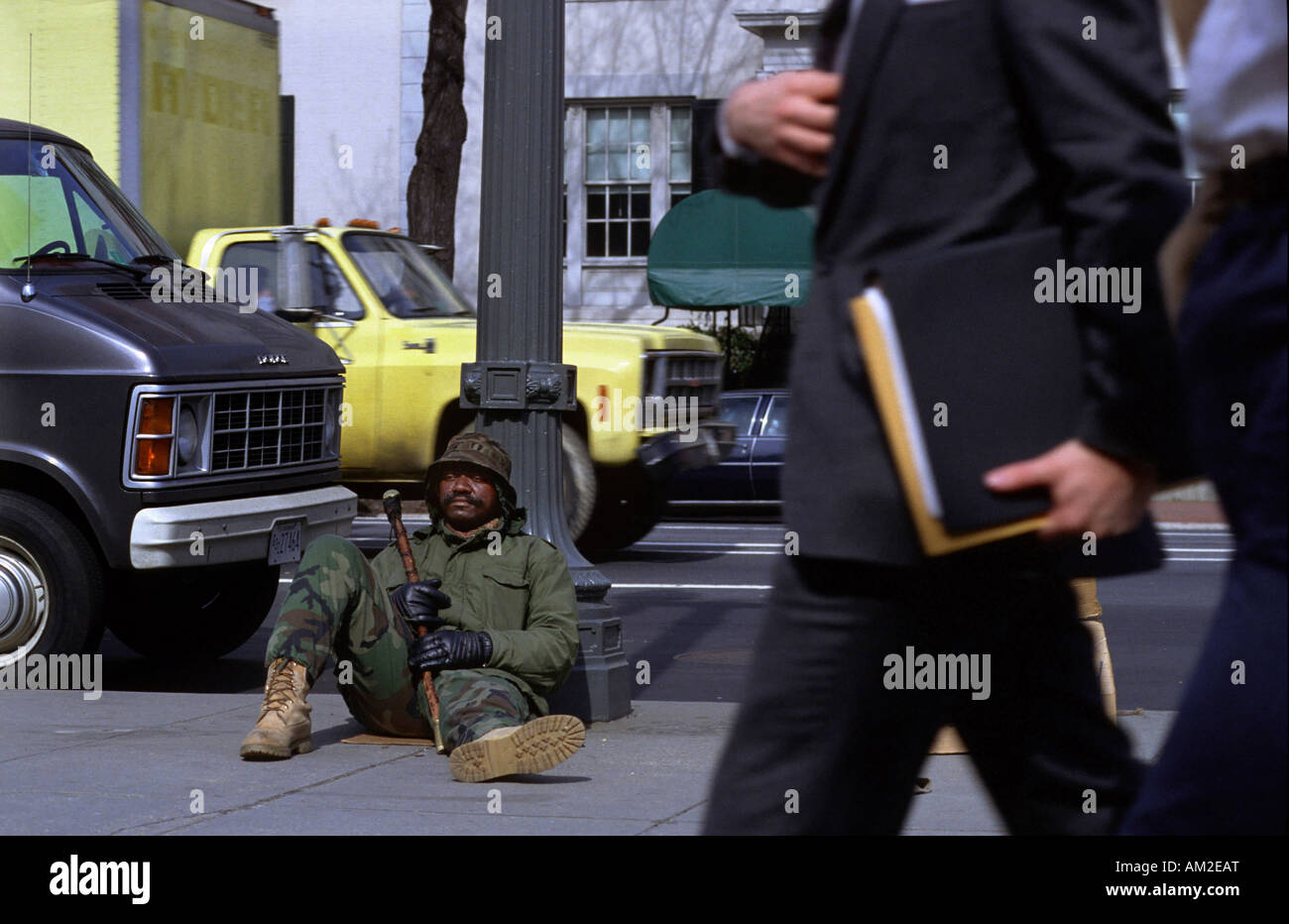 A street person near Blair House with welldressed businessmen in foreground. Stock Photo