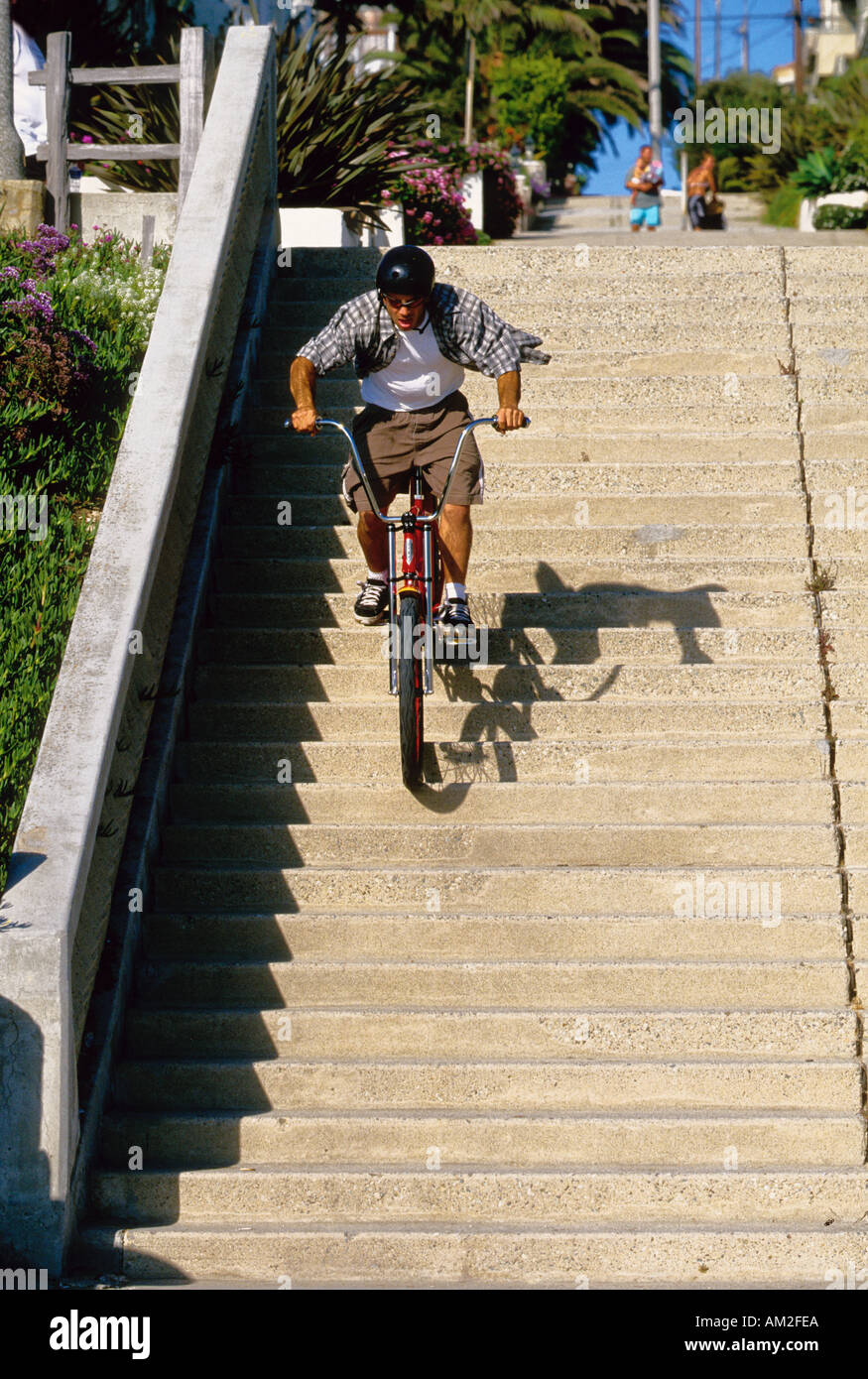A man rides his strand cruiser bike down stairs in Manhattan Beach California USA Stock Photo