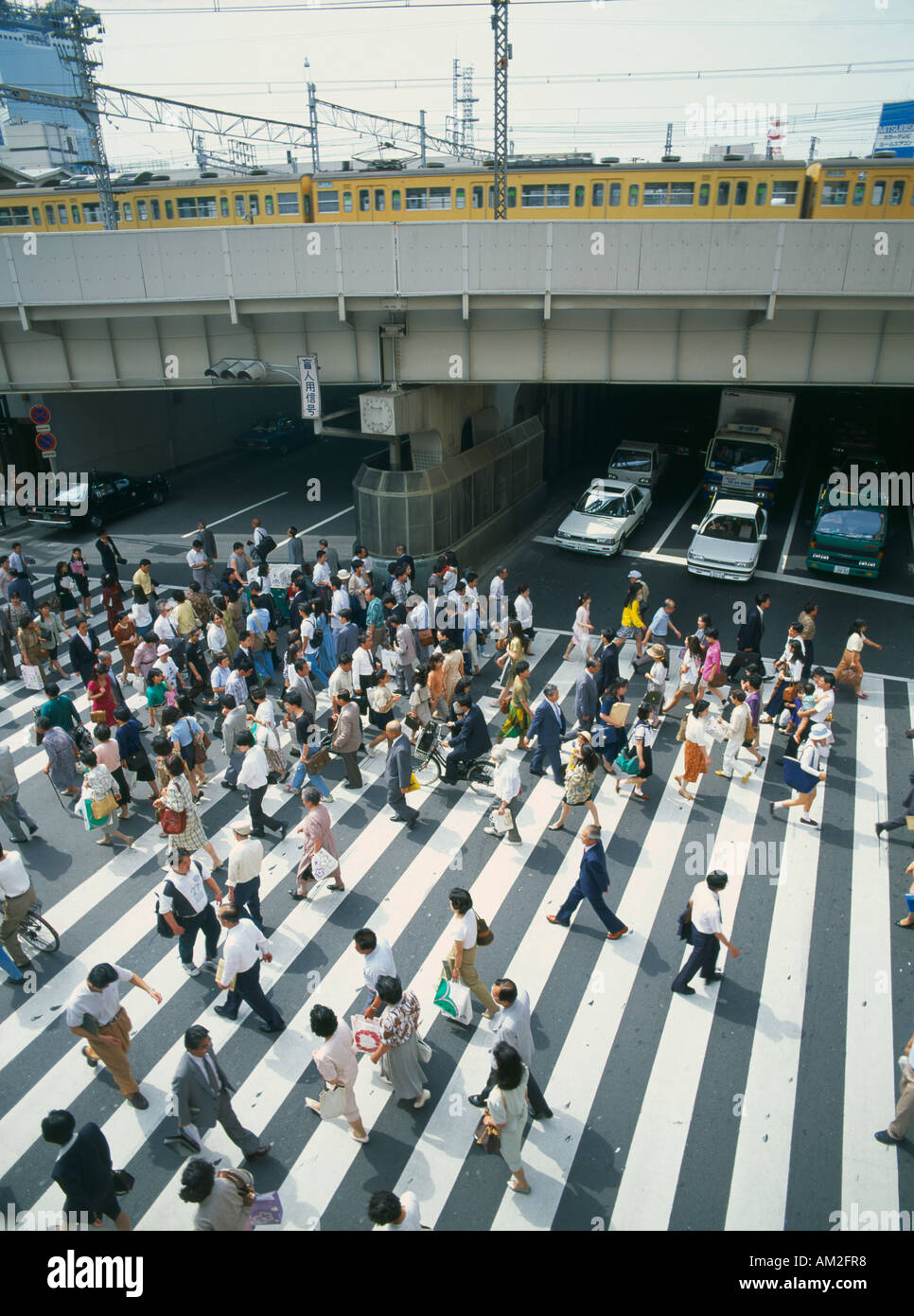 JAPAN Honshu Osaka Umeda District Railway Line train on bridge over road with traffic and people on busy pedestrian crossing Stock Photo