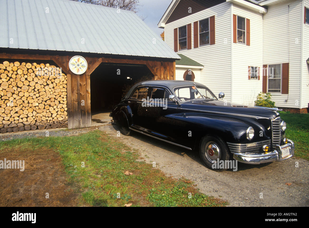 An antique car and stack of firewood in New England Stock Photo
