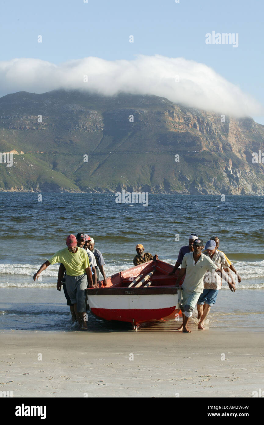 Fishermen pulling boat on the beach, Hout Bay, Cape Town, South Africa Stock Photo