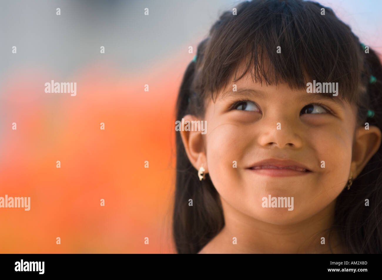 A young Mexican girl smiles mischievously in front of orange flowers