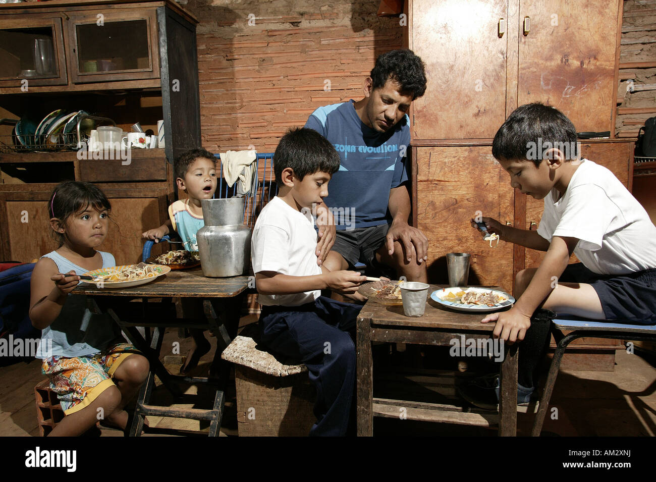 Guarani family eating, single father, in the poor area of Chacarita