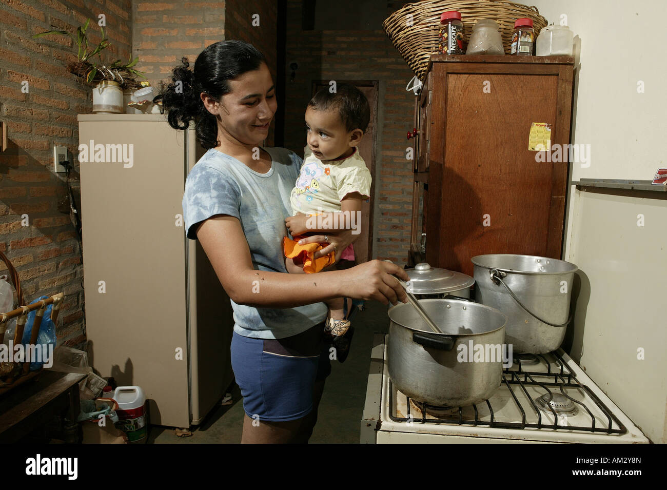 Woman with toddler cooking, 'Comunidad 18 de Agosto', Paraguay, South America Stock Photo