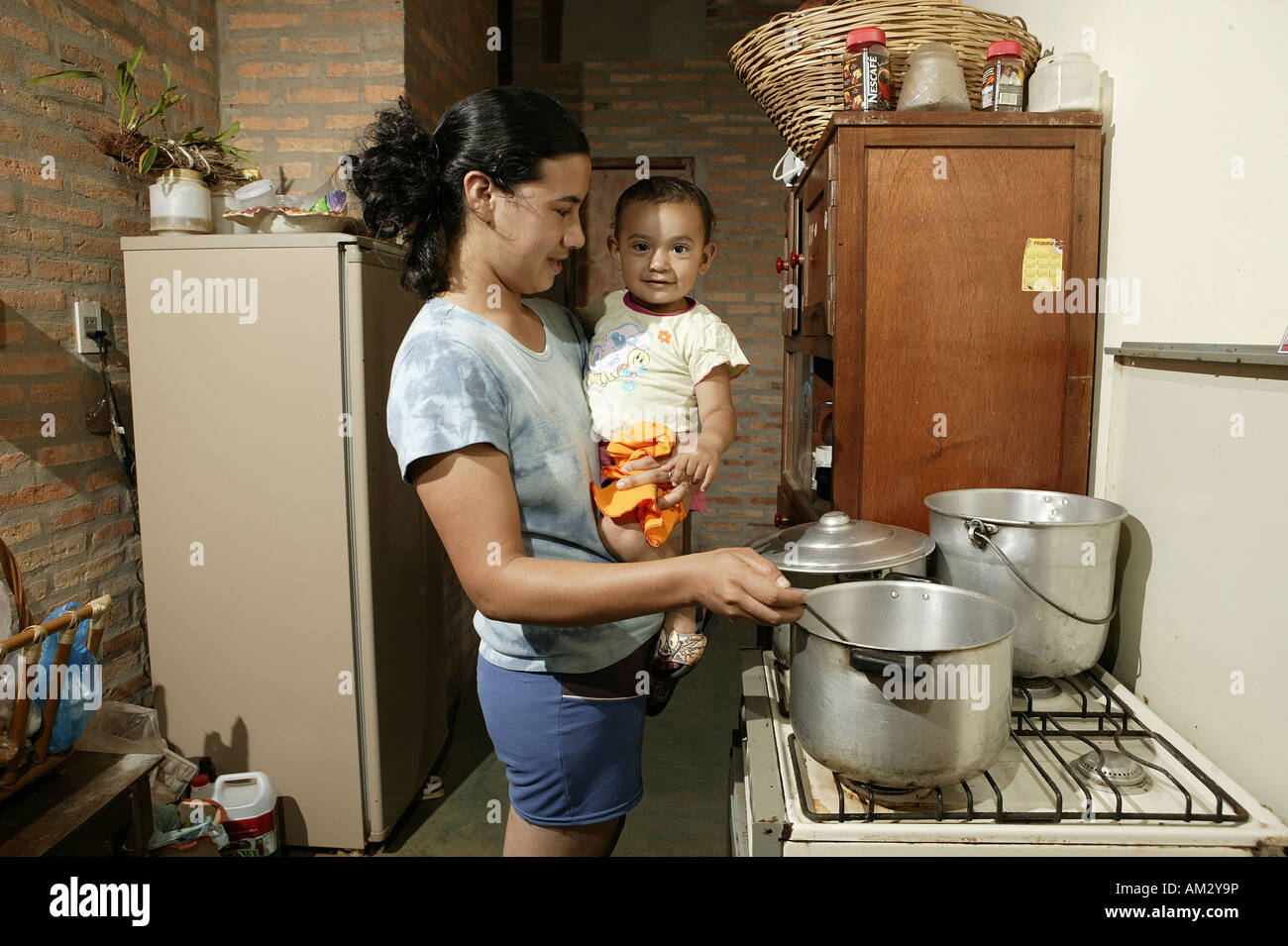Woman with toddler cooking, 'Comunidad 18 de Agosto', Paraguay, South America Stock Photo