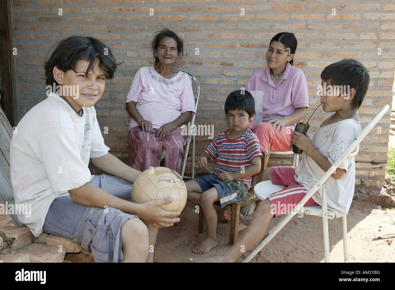 People drinking mate tea in front of a house, 'Comunidad 18 de Agosto', Paraguay, South America Stock Photo
