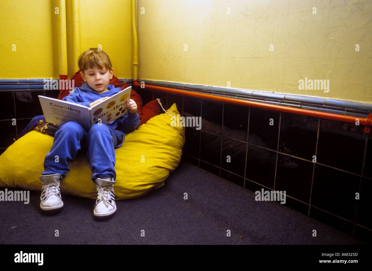 Young boy reading book in corner on big pillow. Stock Photo