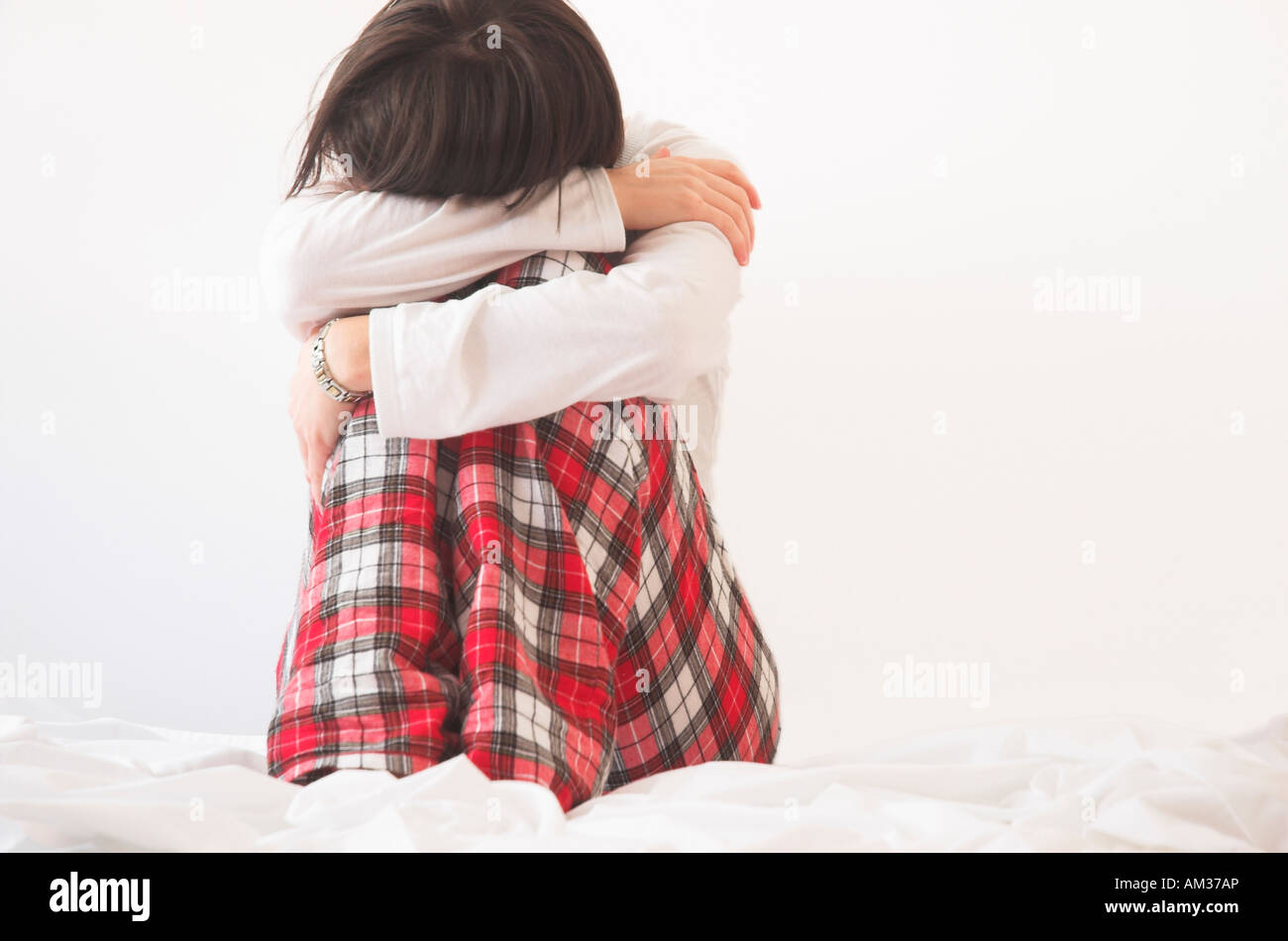 Woman wearing pyjamas sitting on bed Stock Photo Alamy