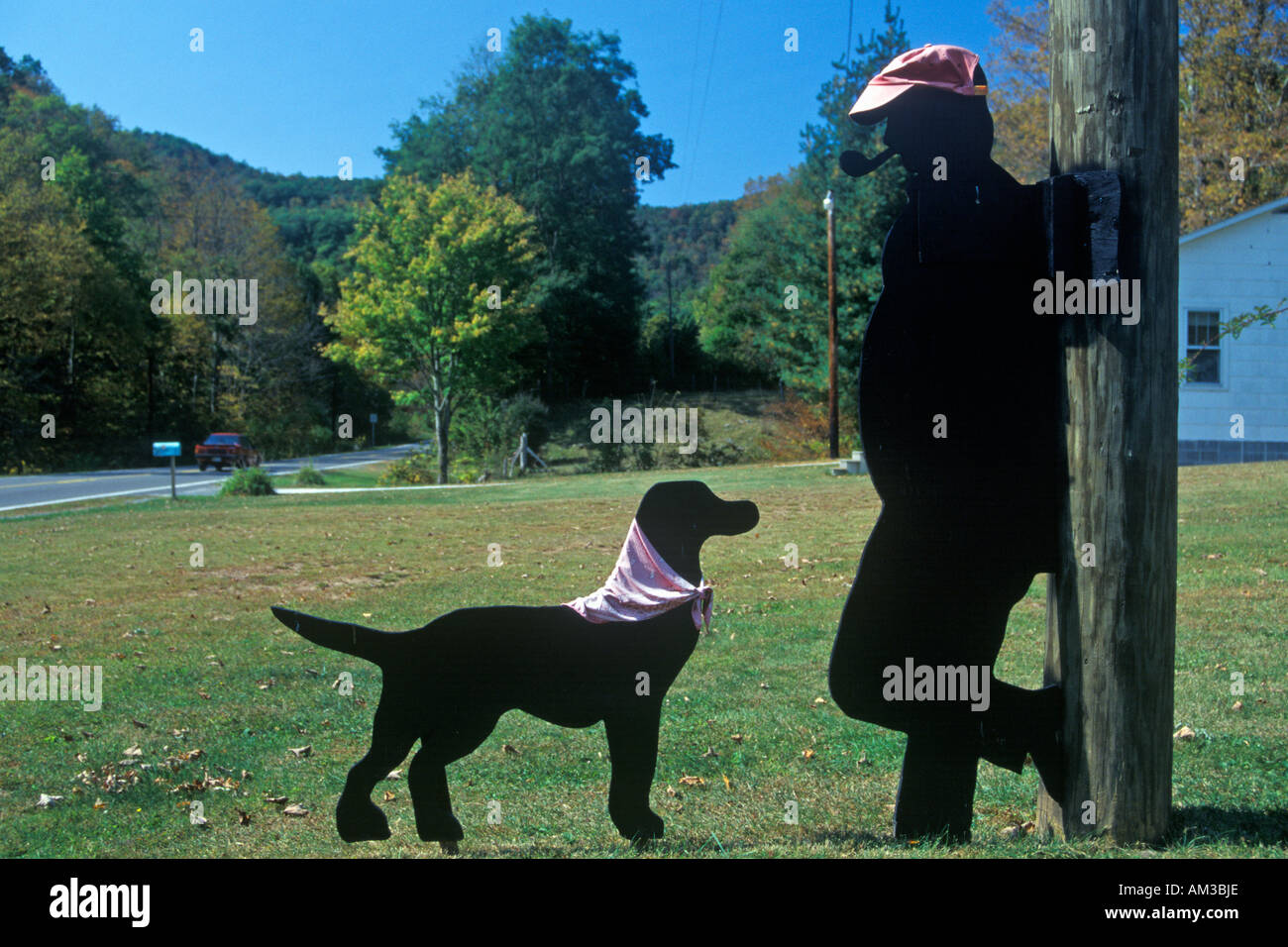 Black dog and man smoking pipe wooden cutouts by roadside Route 39 WV Stock Photo