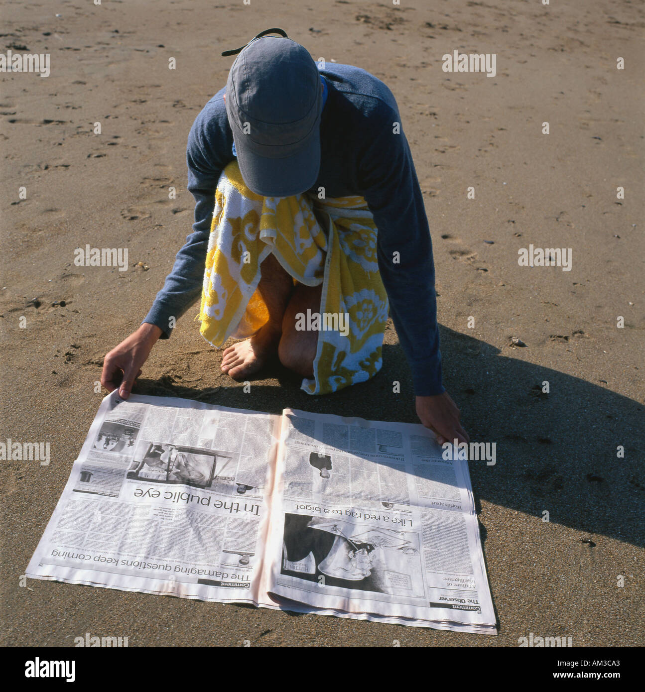 Man reading newspaper on beach Tenby Pembrokeshire South Wales Stock Photo