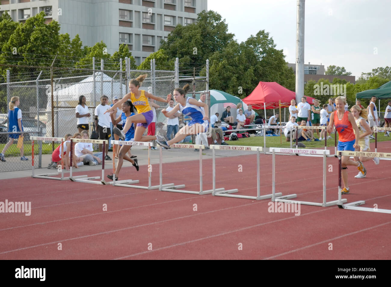 Teenage girl hurdlers at a high school track and field district meet