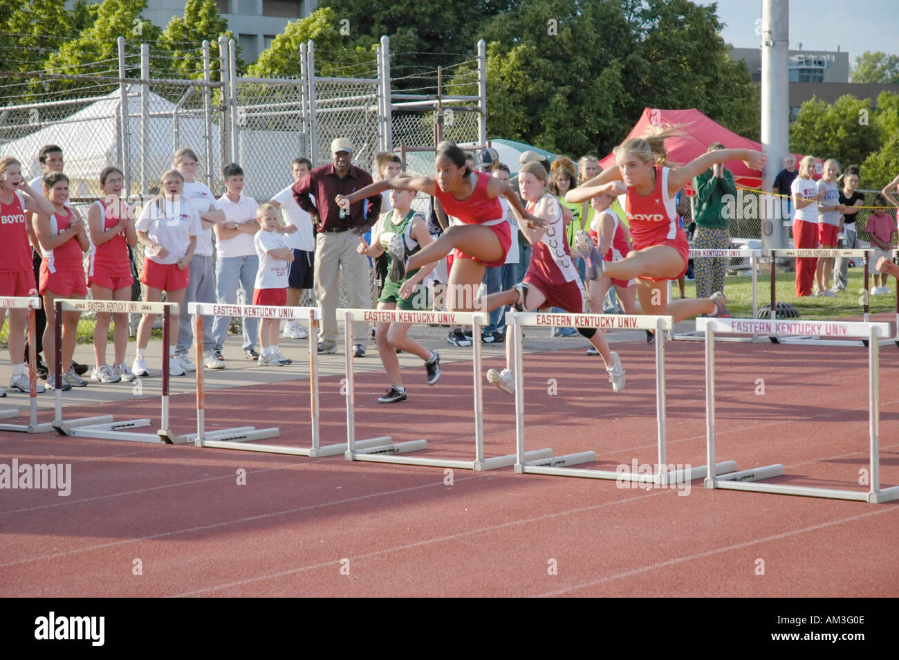 Teenage girl hurdlers at a high school track and field district meet