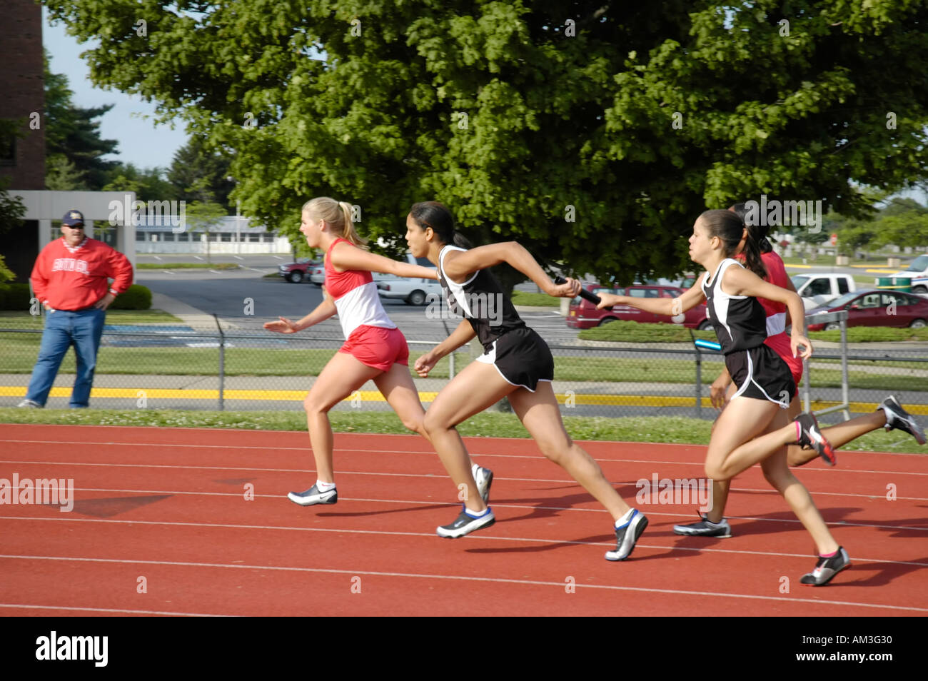 Teenage girl relay race runners at a high school track and field