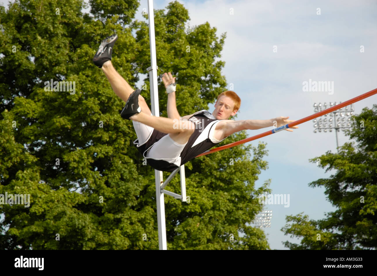 Teenage boy pole vaulter clearing the bar at a high school track and