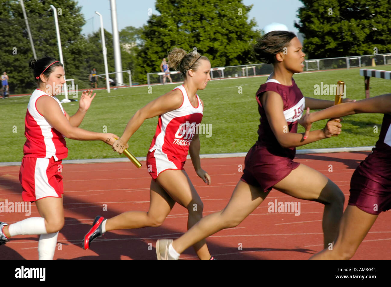 Teenage girl relay race runners at a high school track and field Stock