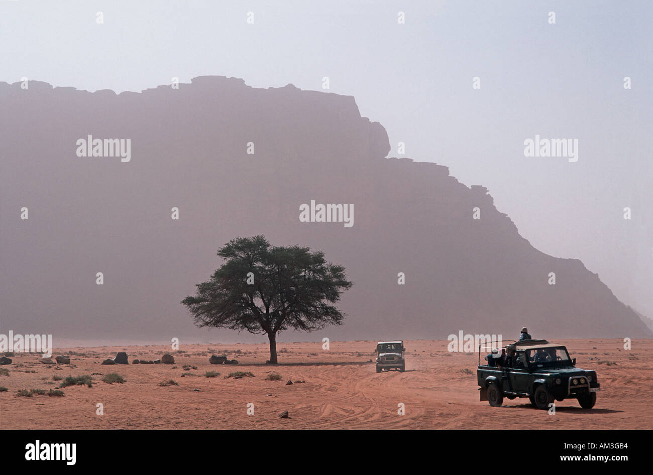 Floor of the desert with outcrops called Jebels in the distance Jeeps crossing the desert floor Wadi Rum Jordan Stock Photo