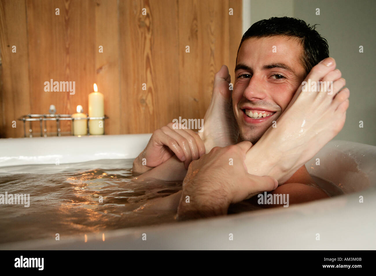 Man holding woman s feet in roll top bath Stock Photo