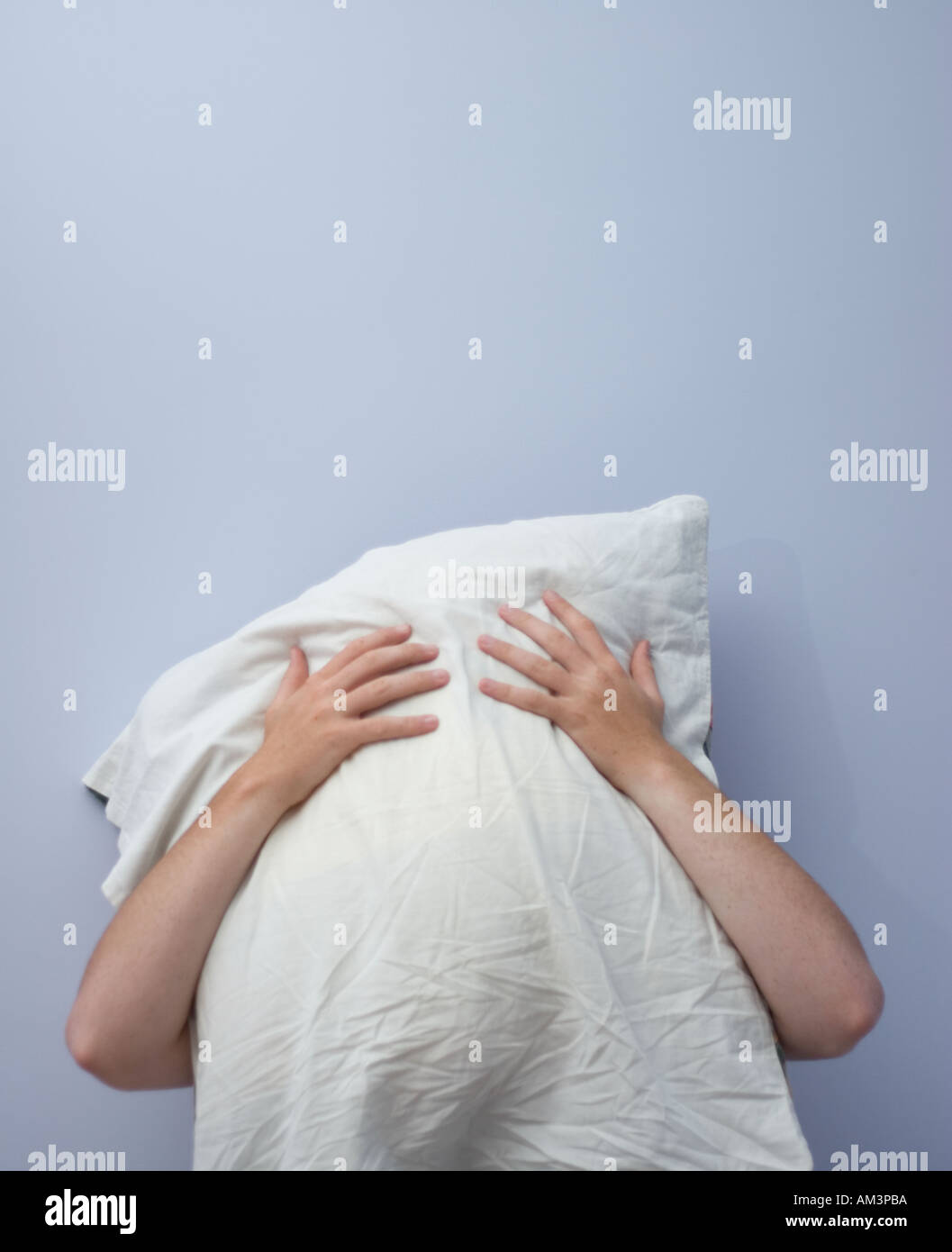 Young Man Covering His Face With A White Pillow In Front Of A