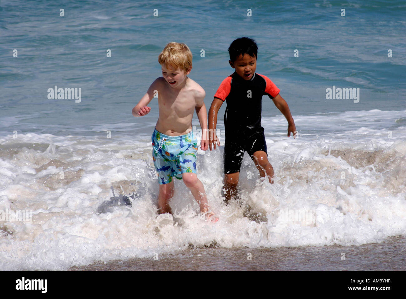 Two 5 year old boys running in the sea Stock Photo