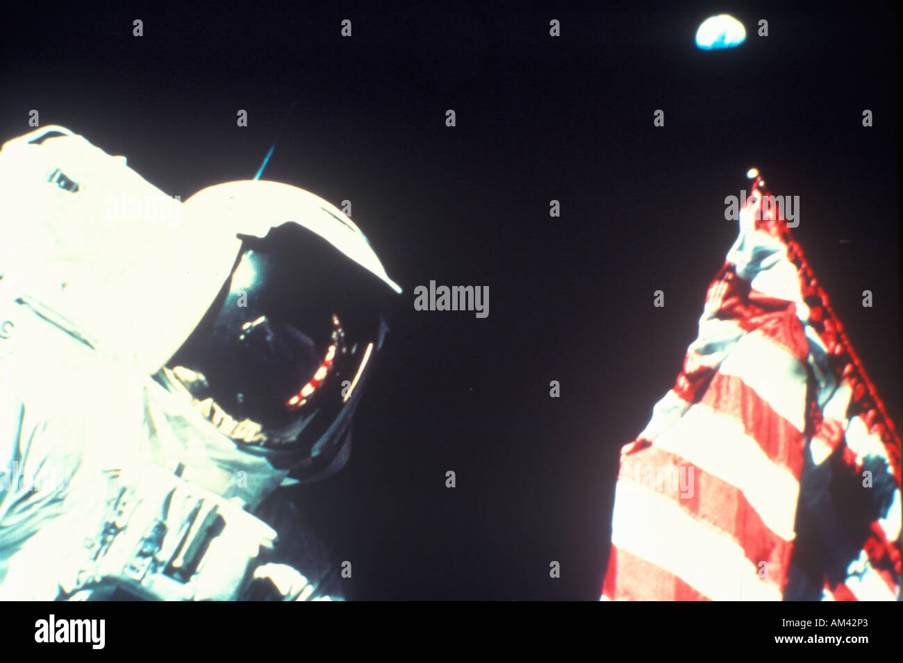 Astronaut and American flag below blue Earth in starless sky Stock Photo