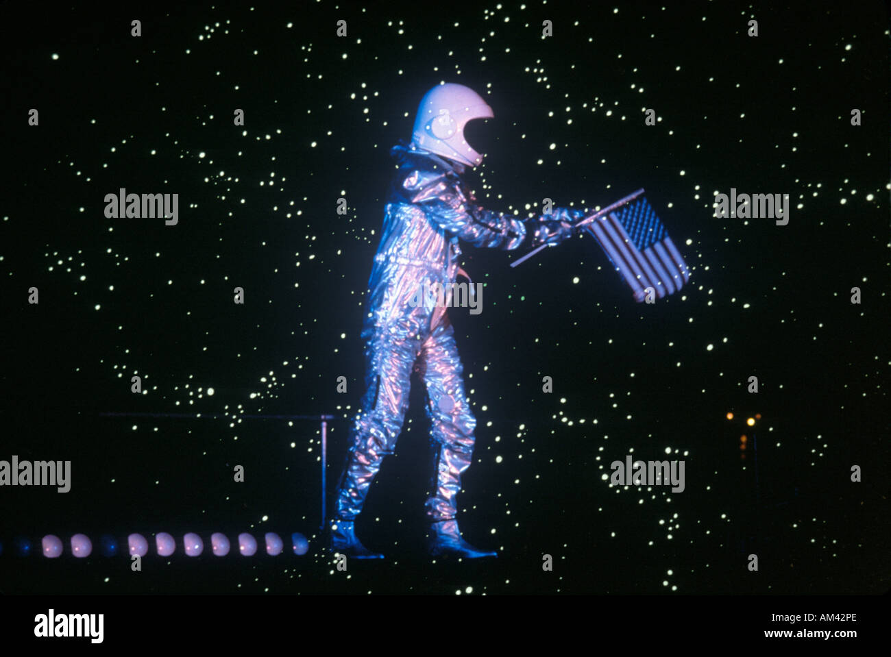 An astronaut holding an American flag walking through a starfield Stock Photo