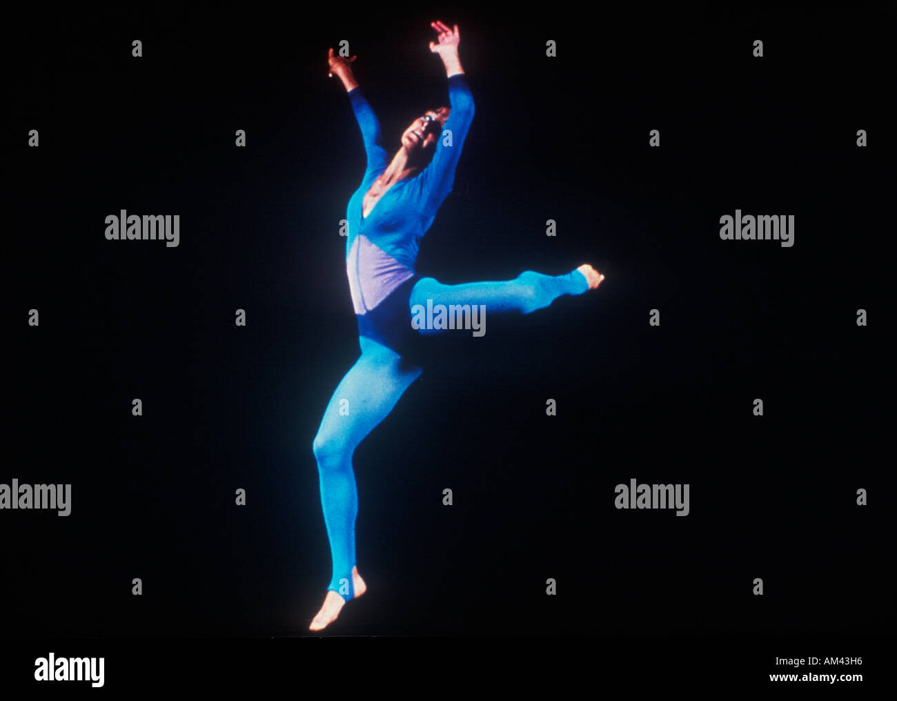A dancer stretching on a darkened stage Stock Photo