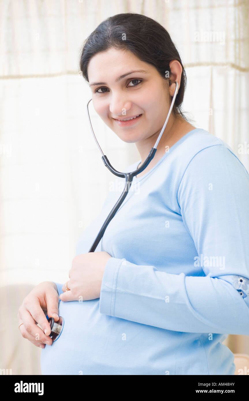 Close-up of a pregnant woman putting a stethoscope on her abdomen Stock Photo
