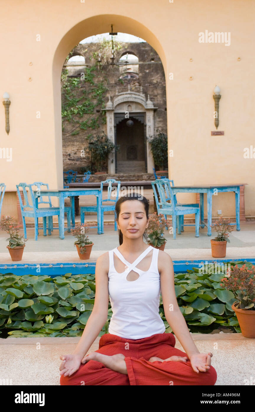 Young woman sitting in a lotus position with her eyes closed, Neemrana ...