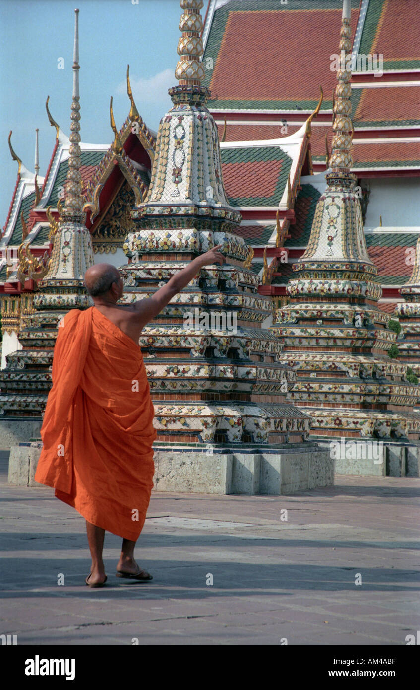 Monk in a colourful orange robe walks by a temple in Thailand Stock ...
