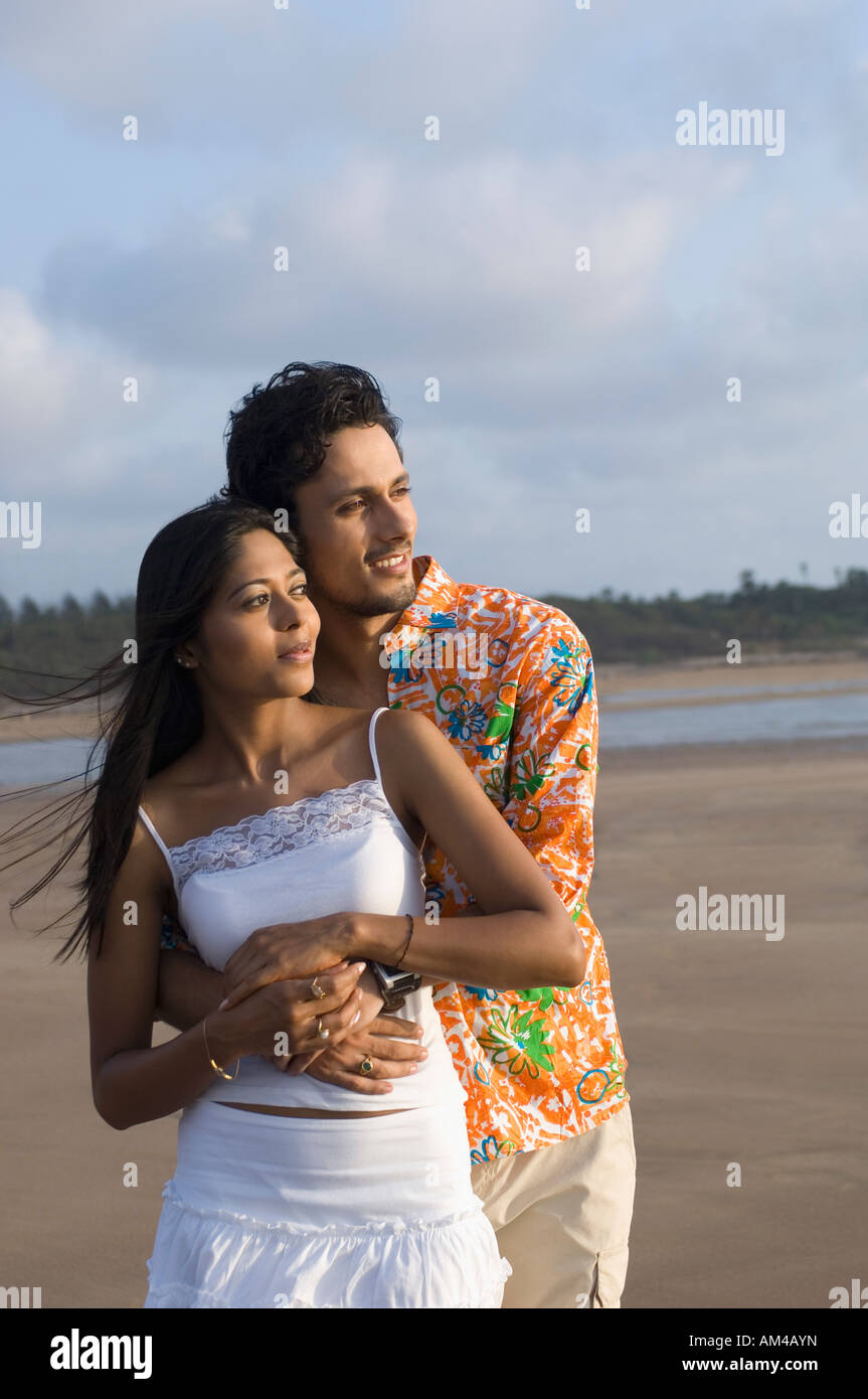 Young man embracing a young woman from behind on the beach Stock Photo ...