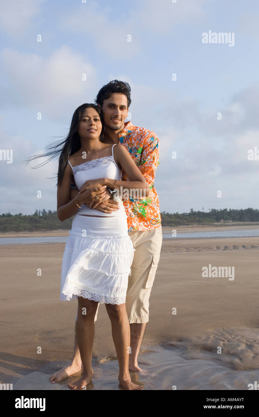 Portrait of a young man embracing a young woman from behind on the ...