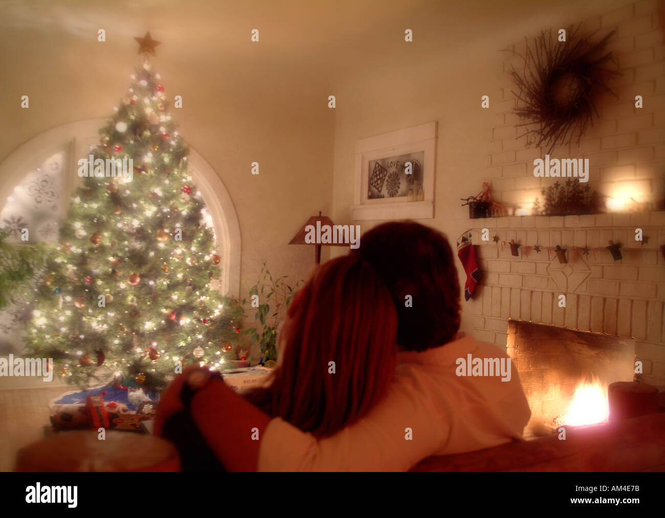 couple on the couch by the Christmas tree and fireplace Stock Photo