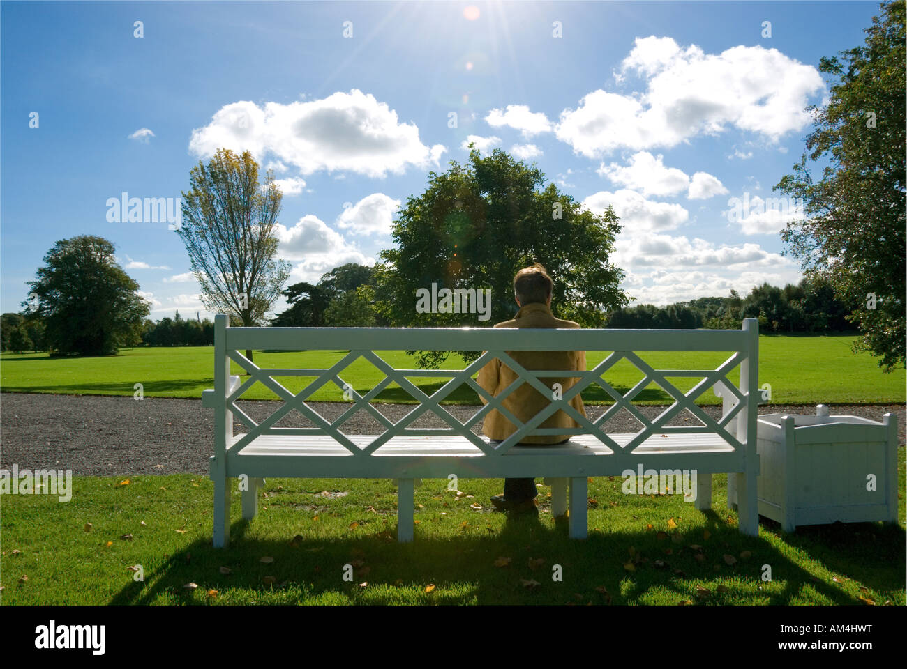 A woman sits and ponders on a park bench Stock Photo