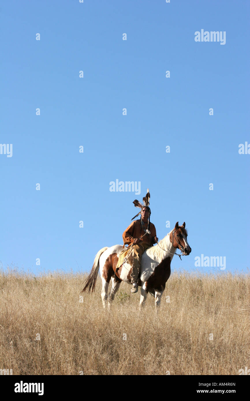 A Native American Indian man siting bareback on a horse riding the prairie of South Dakota Stock Photo