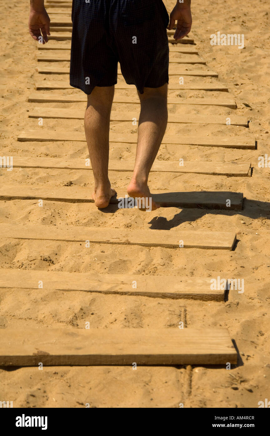 man in trunks walking on wooden steps on the beach Stock Photo Alamy