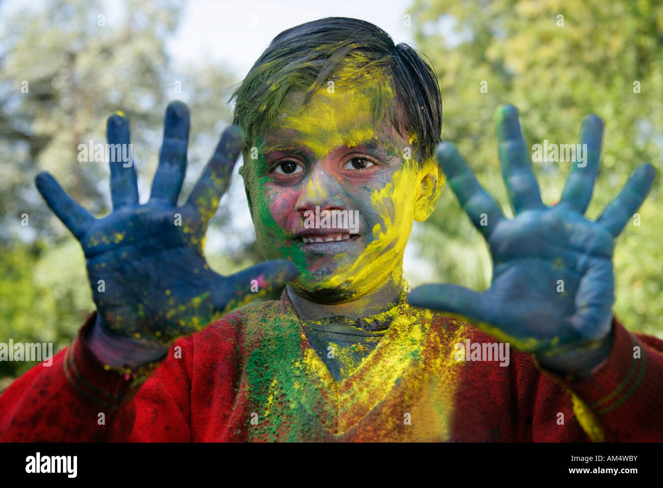 A smiling young boy shows off his colored hands and face during festival of Holi in India. Stock Photo