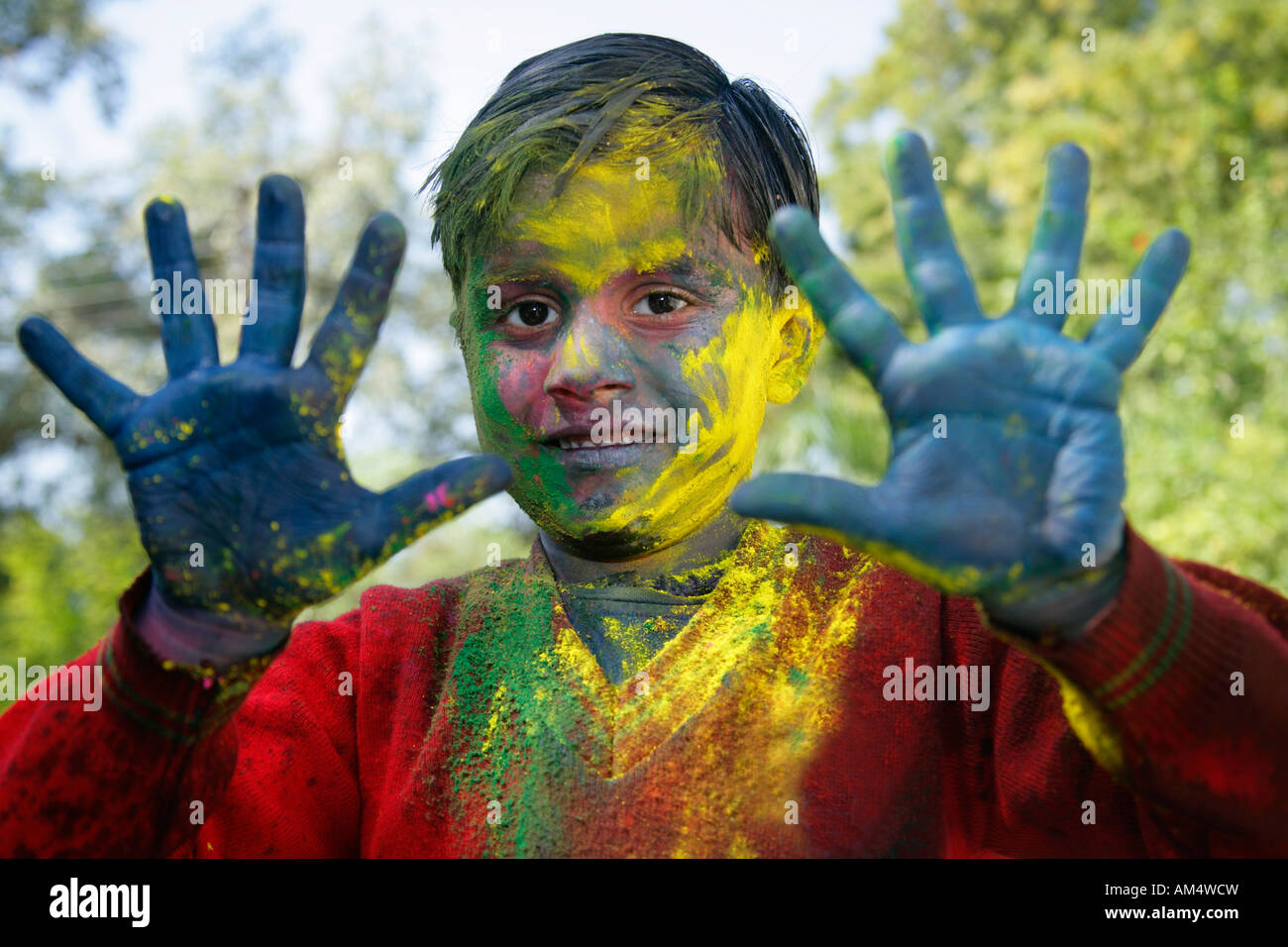 A smiling young boy shows off his colored hands and face during festival of Holi in India. Stock Photo