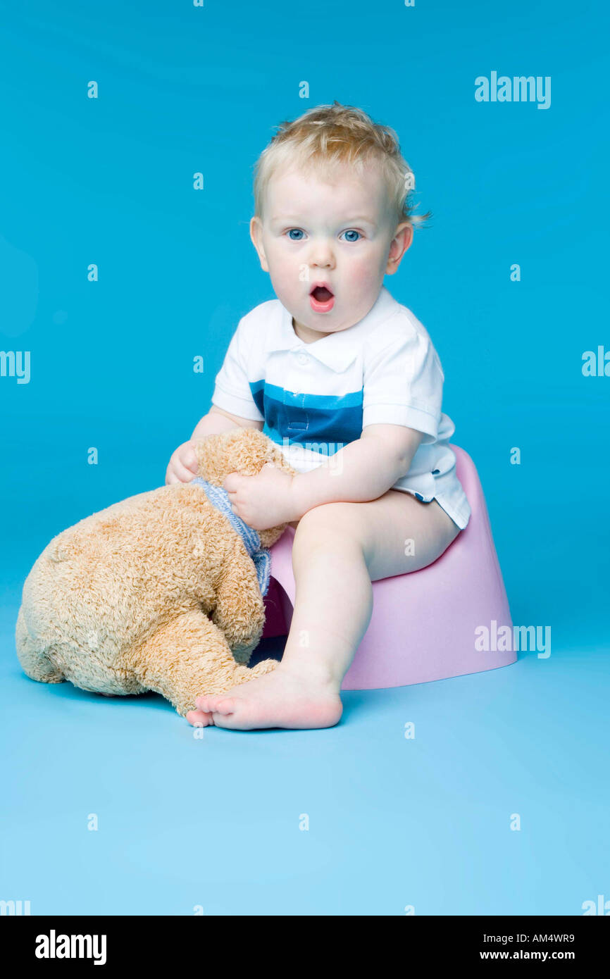 small boy sitting with teddy bear on toilet Stock Photo Alamy