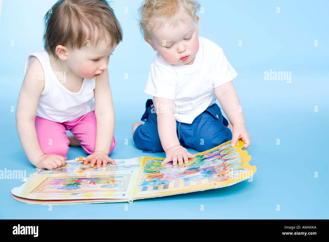 toddler boy and toddler girl looking at book Stock Photo - Alamy