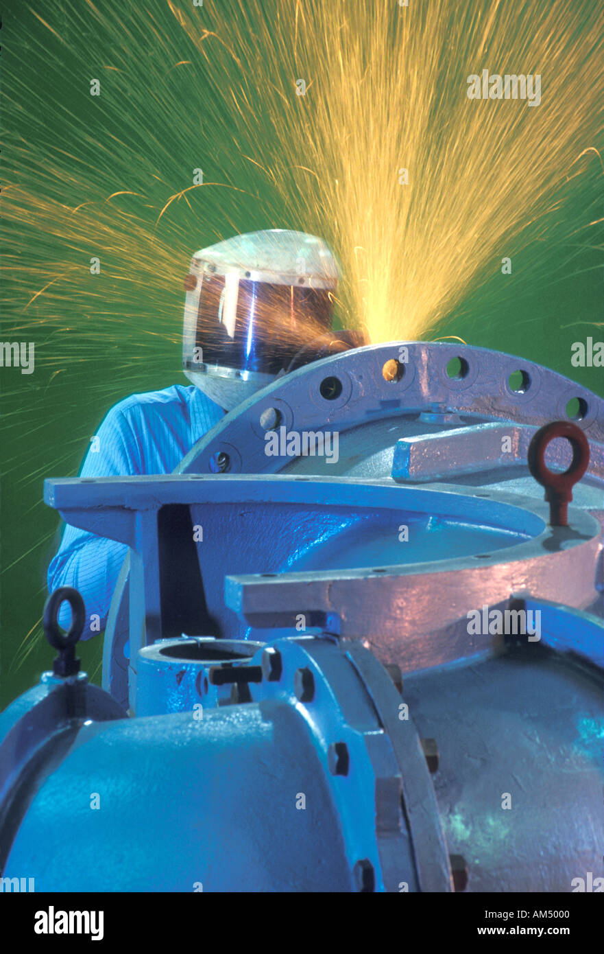 man grinding on an industrial metal pipe fabrication Stock Photo