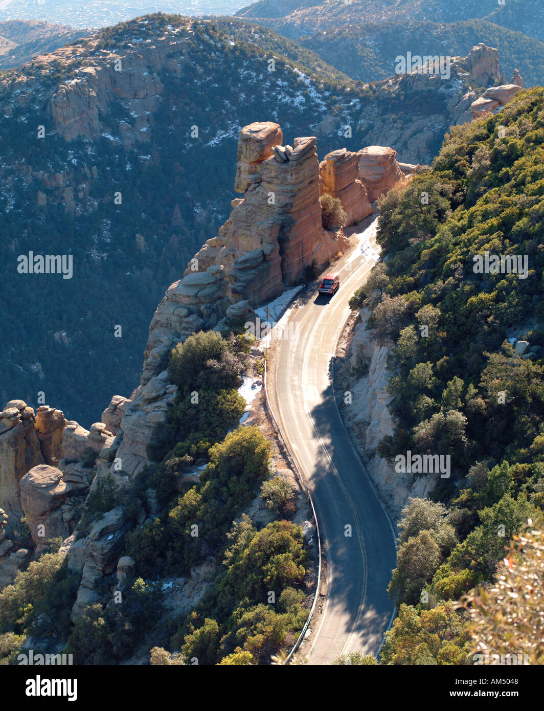 twisting mountain road with a car going around a switch back turn. Stock Photo