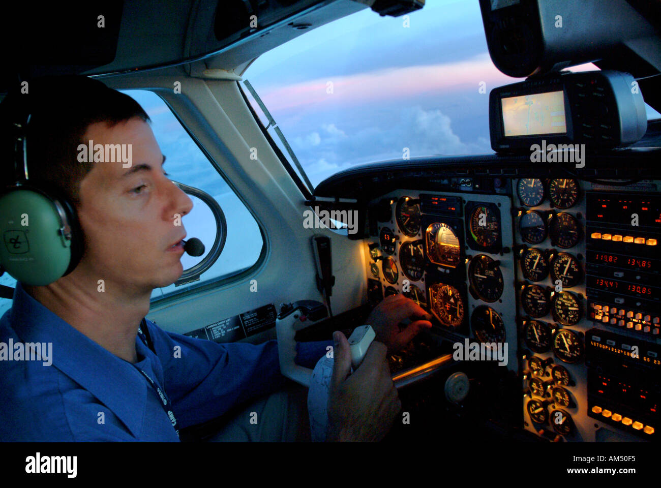 Pilot in the cockpit of a twin engine turbo prop airplane at dusk Stock