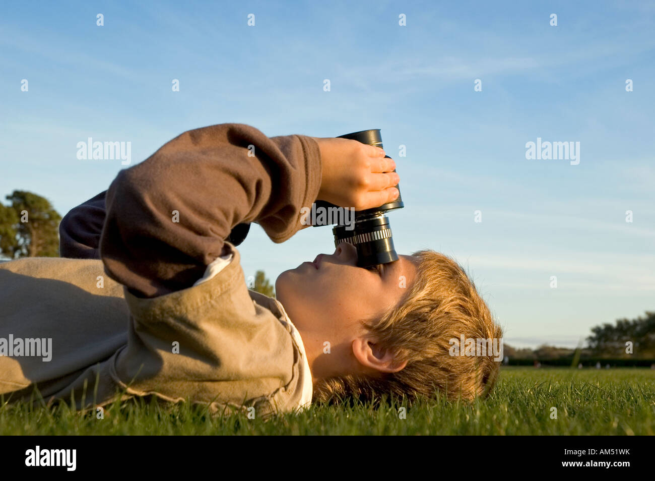 young boy lying down looking up at the sky with binoculars Stock Photo -  Alamy