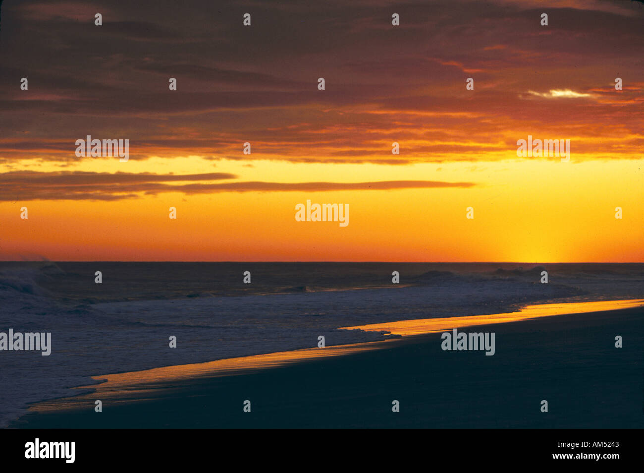 A golden sunset over a sandy ocean beach Stock Photo
