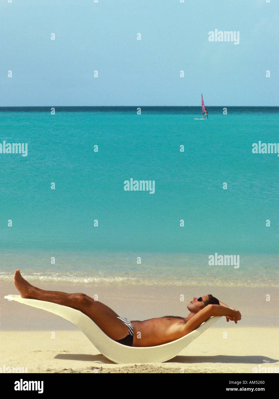 man suns himself on a tropical beach in the Caribbean. Stock Photo