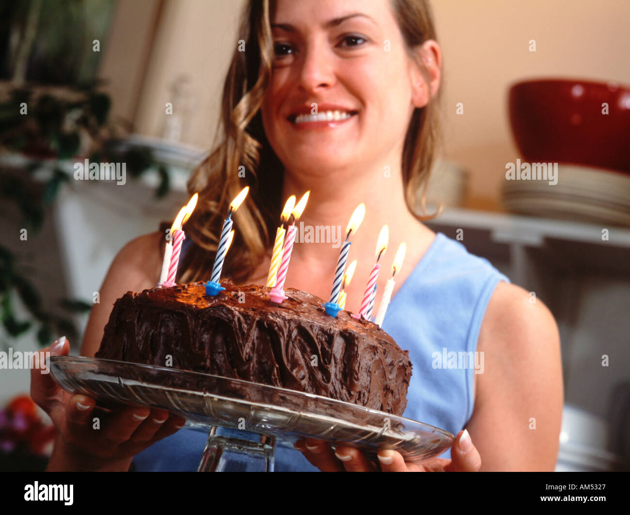 A woman carries birthday cake with lit candles Stock Photo Alamy