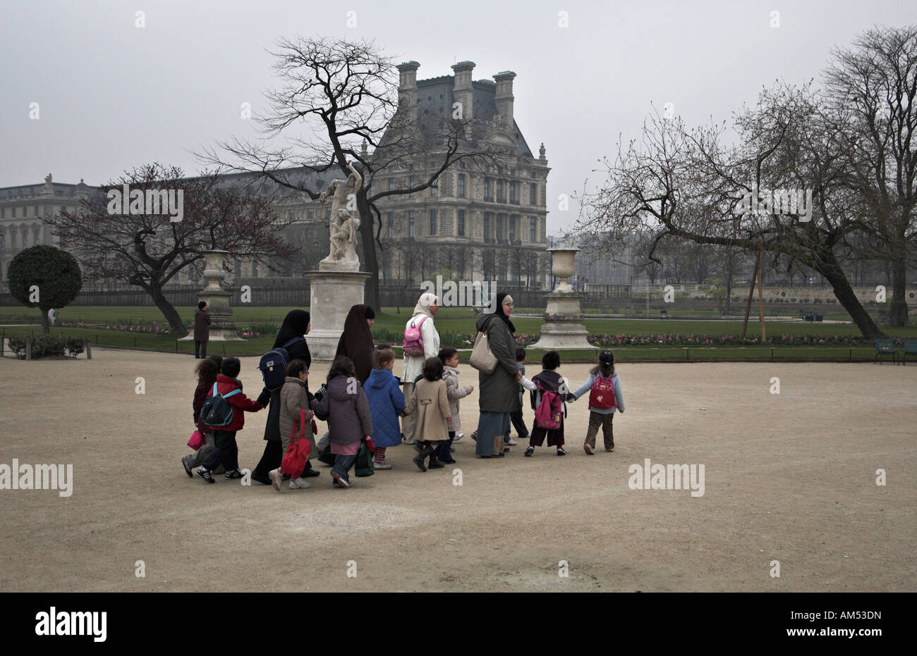 a group of young muslim women wearing burkas and children walking across the Tuileries Garden Paris France Stock Photo